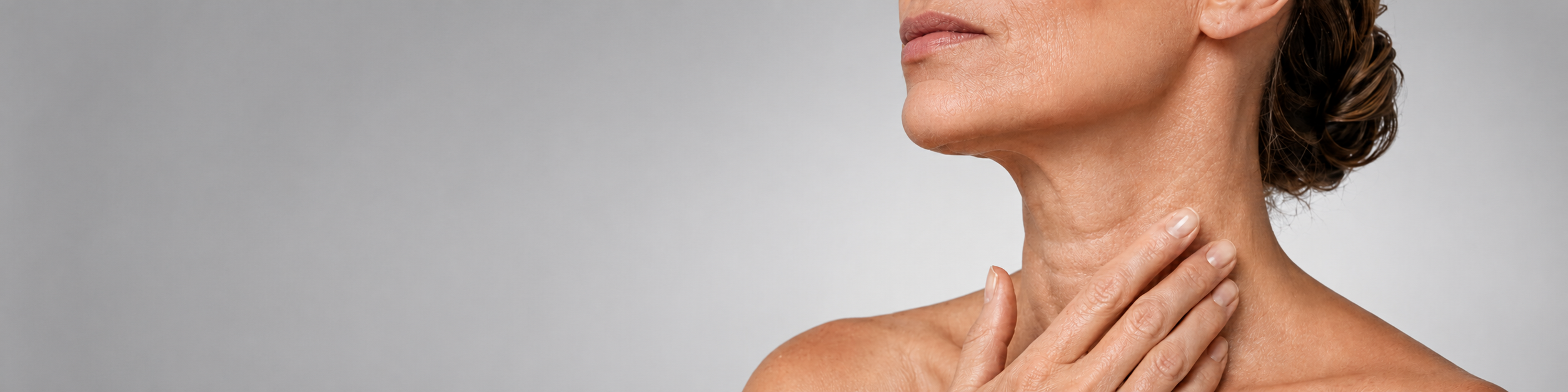 Mujer de 47 años aplicando cuidado cosmético en el cuello para mejorar la apariencia de los anillos de Venus y las líneas horizontales.